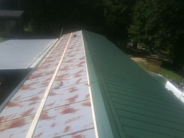 Old rusted panels beside newly installed green metal roofing — Wind Damage Roof Repair by Roofing Brothers in Pekin