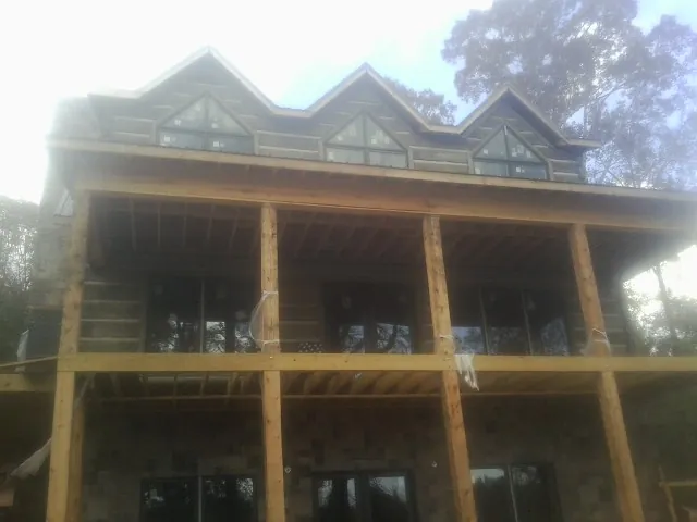 Dormers and porch framing on a large log home under construction — Roof Coating work by our crew in Pekin