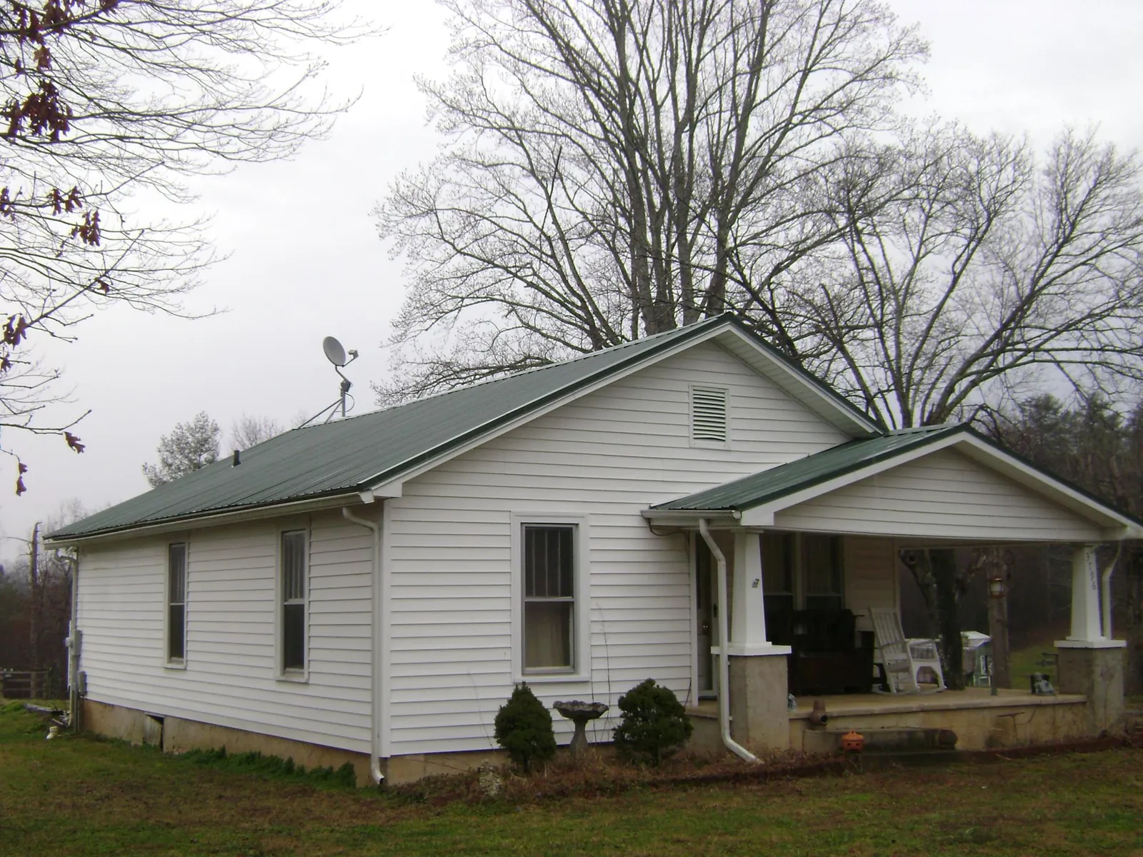 Green metal roof on a white bungalow with a side porch in Pekin
