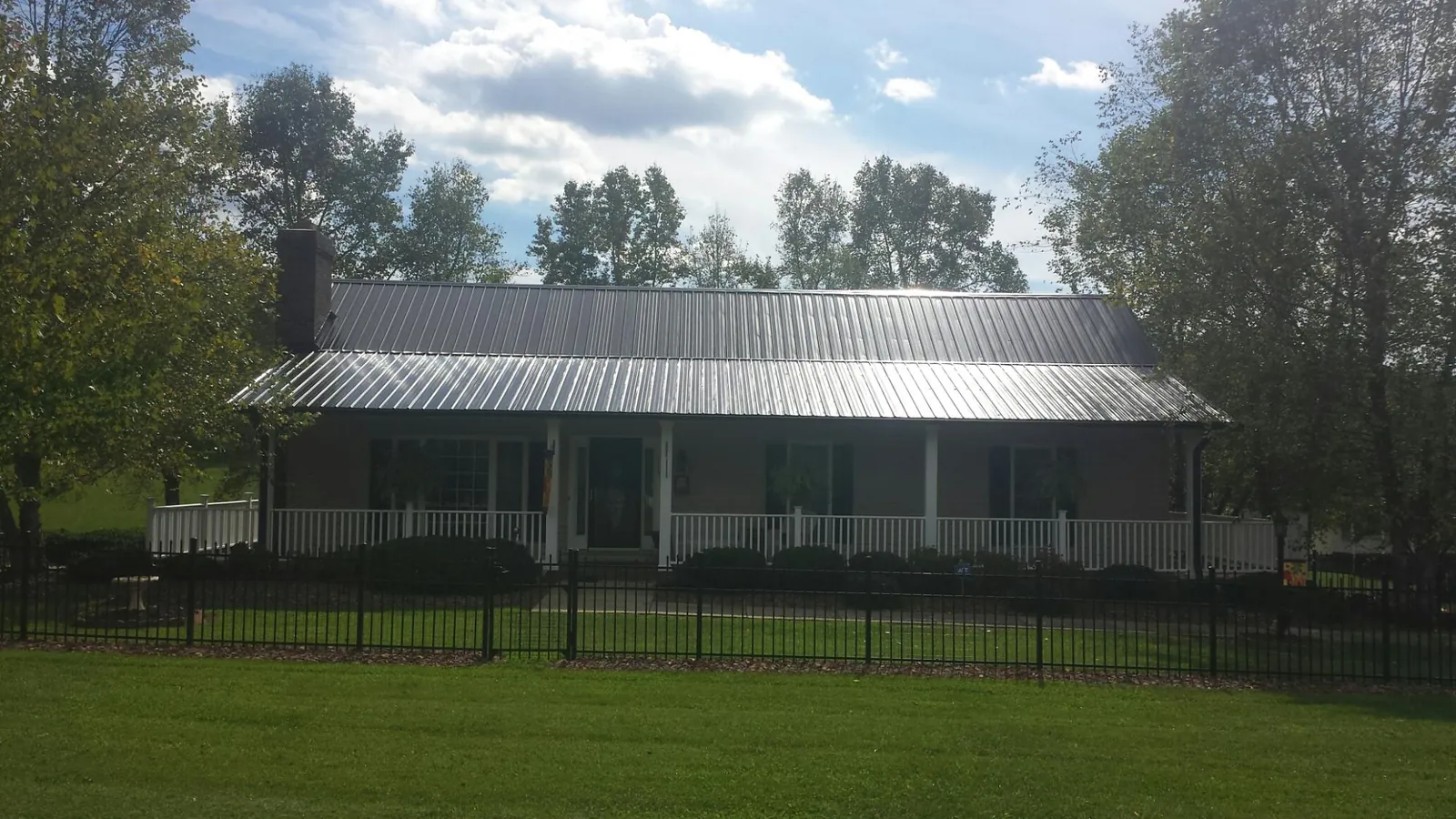 Gray metal roof on a brick ranch with a full width front porch — Gutter Guard Installation work by our crew in Pekin
